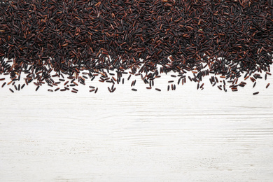 Photo of Brown rice on white wooden table, top view