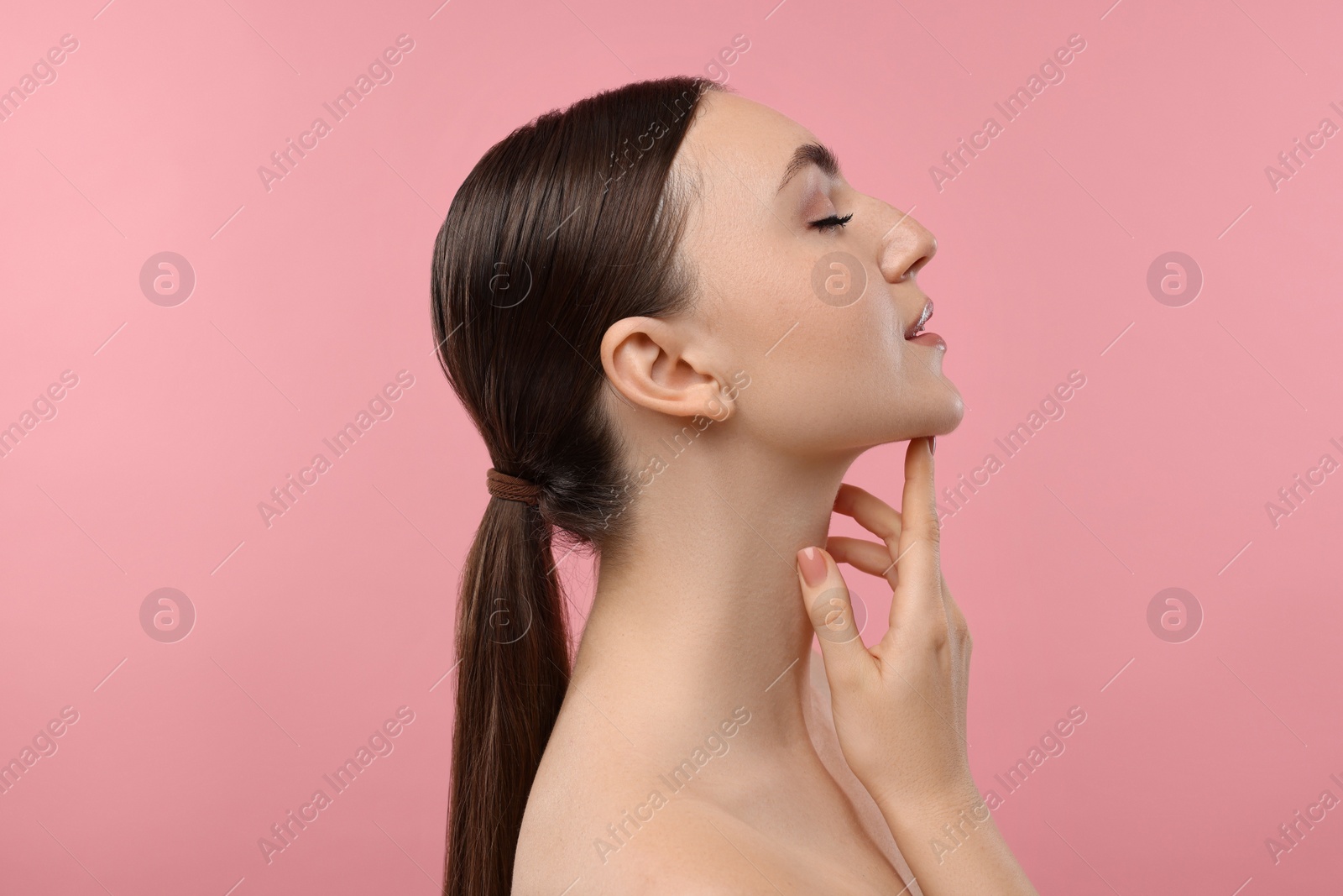 Photo of Beautiful woman touching her chin on pink background