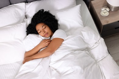 Photo of Beautiful young woman sleeping in soft bed at home, above view