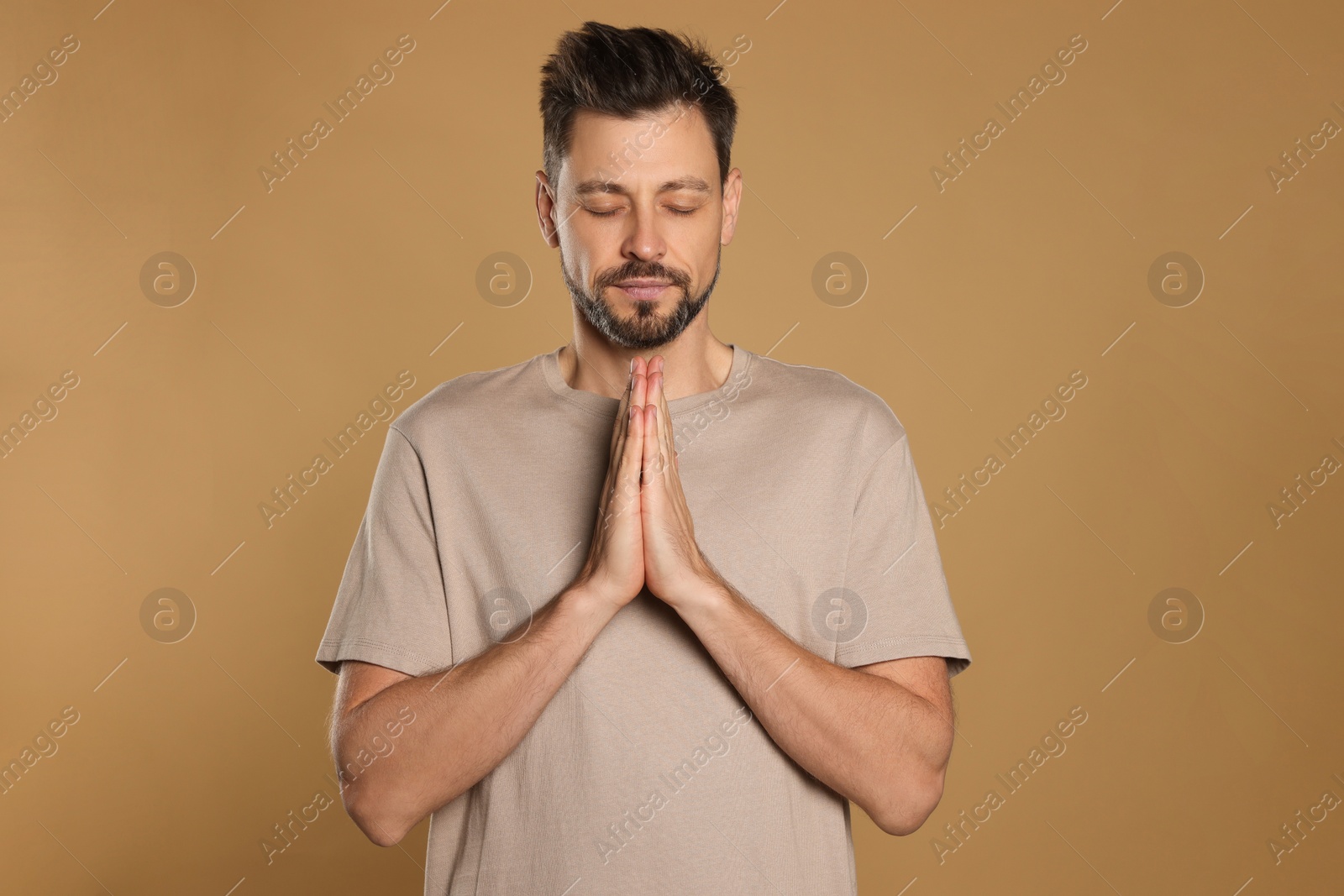 Photo of Man with clasped hands praying on beige background