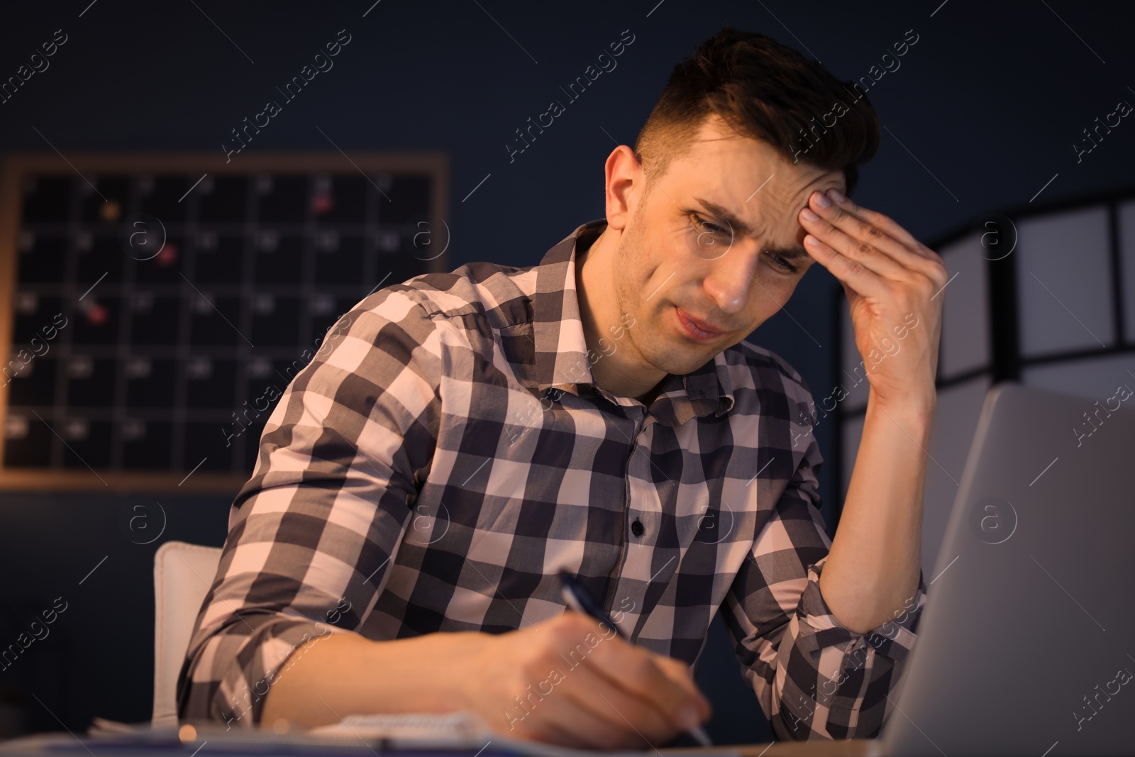 Photo of Overworked man with headache in office