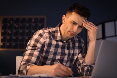 Photo of Overworked man with headache in office