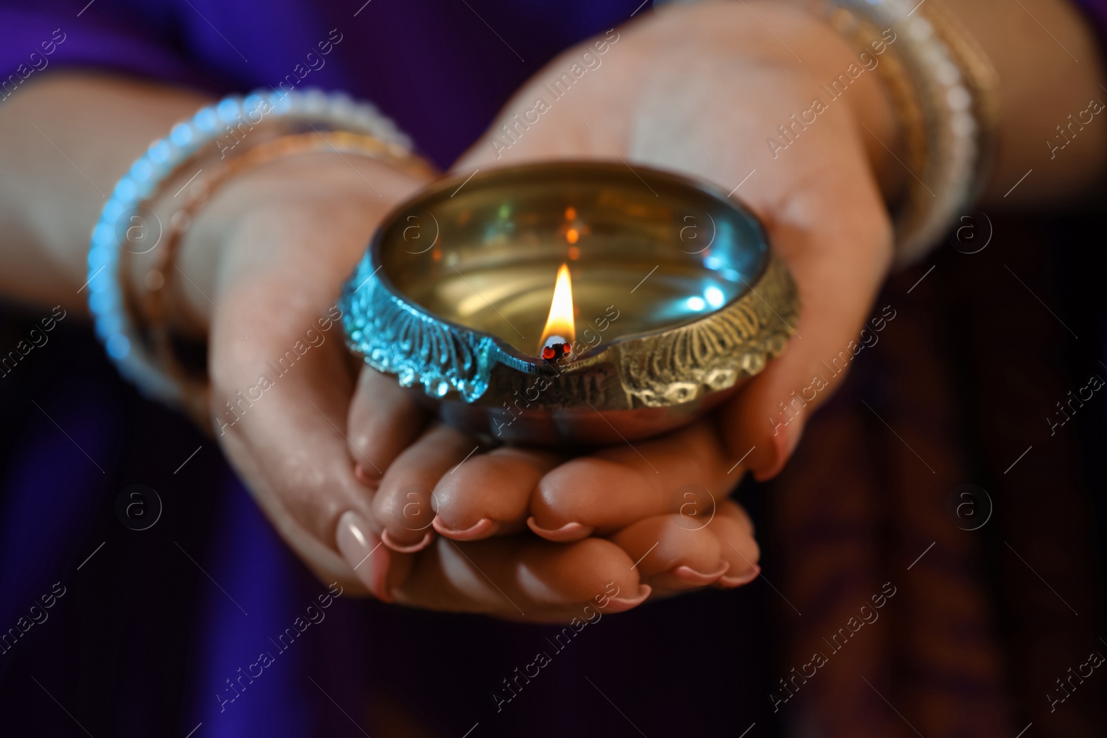 Photo of Woman holding lit diya lamp in hands, closeup. Diwali celebration