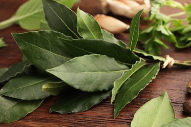 Aromatic fresh bay leaves on wooden table, closeup