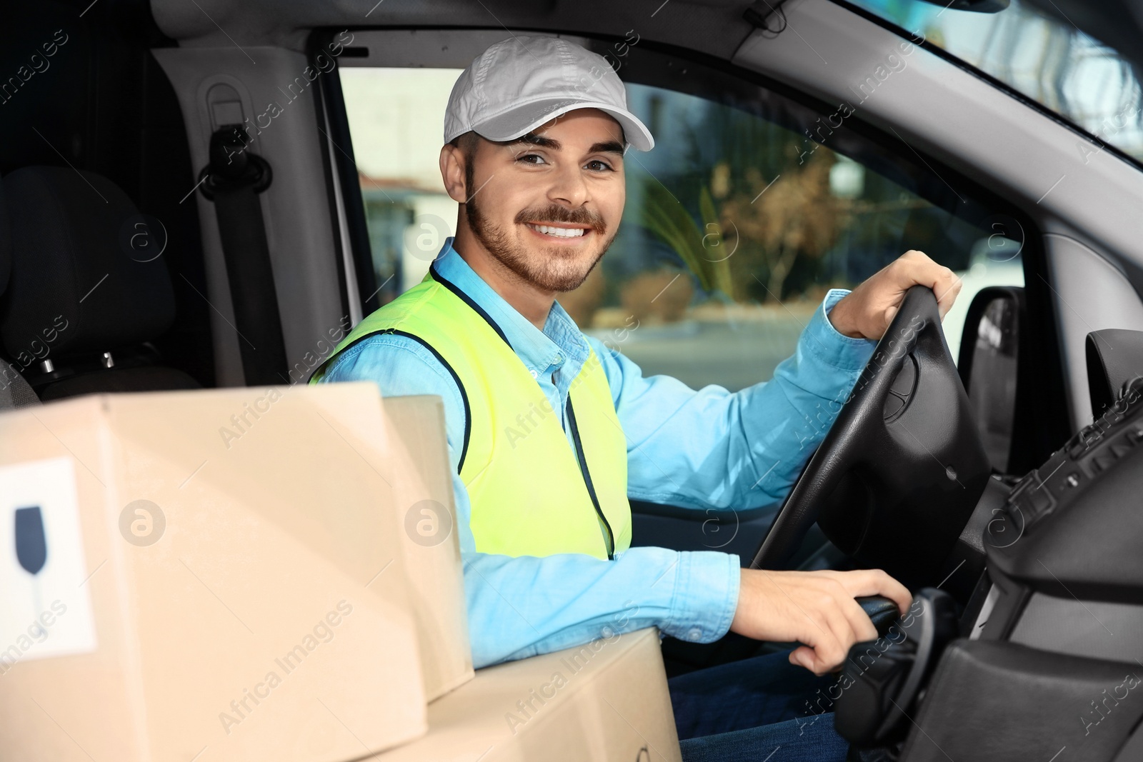 Photo of Young courier driving delivery van with parcels