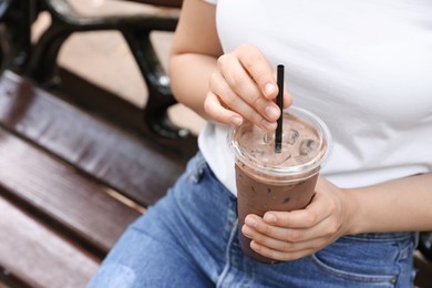 Photo of Woman holding takeaway plastic cup with cold coffee drink outdoors, closeup. Space for text