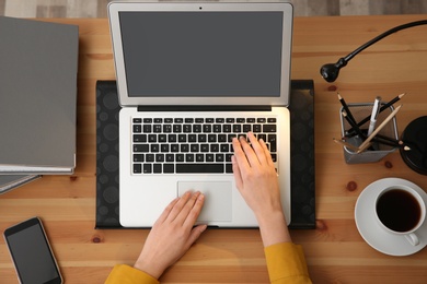 Photo of Woman using modern laptop at table, top view