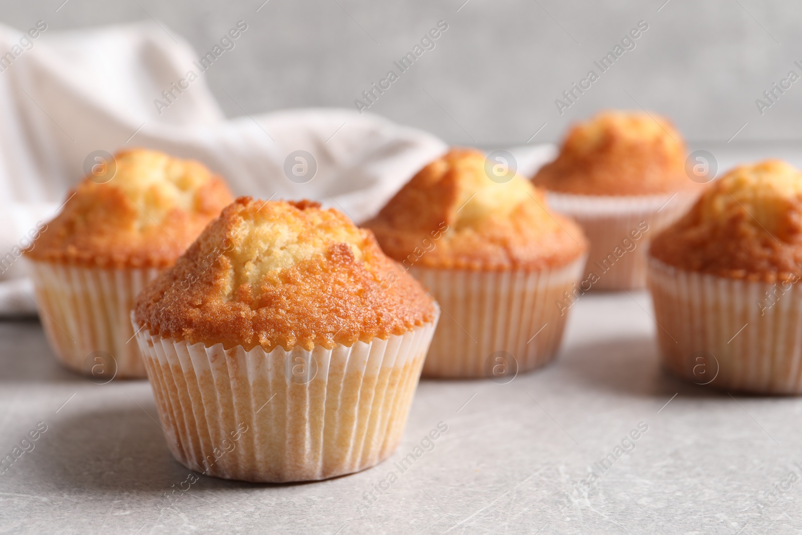 Photo of Tasty muffins on light grey table, closeup. Fresh pastry