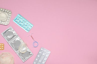 Photo of Contraceptive pills, condoms and intrauterine device on pink background, flat lay and space for text. Different birth control methods