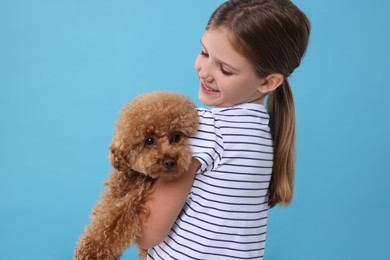 Little child with cute puppy on light blue background. Lovely pet