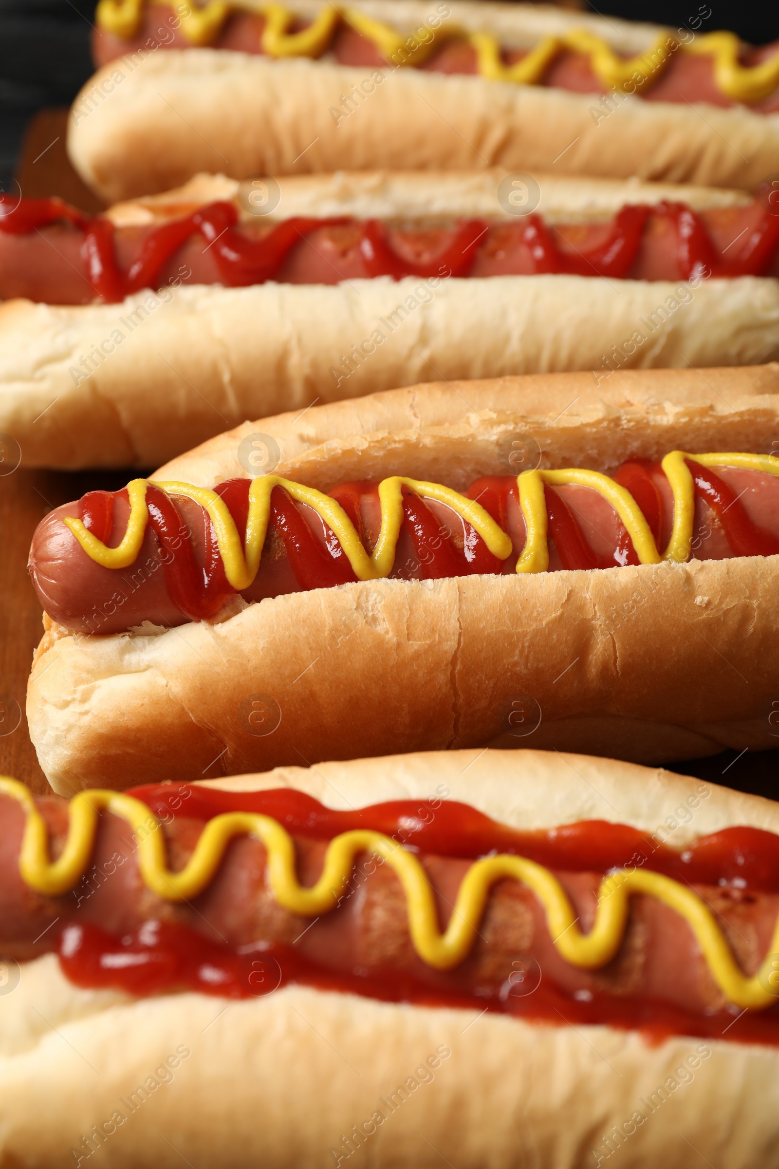 Photo of Delicious hot dogs with mustard and ketchup on wooden table, closeup