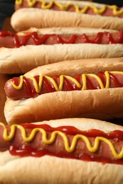 Photo of Delicious hot dogs with mustard and ketchup on wooden table, closeup