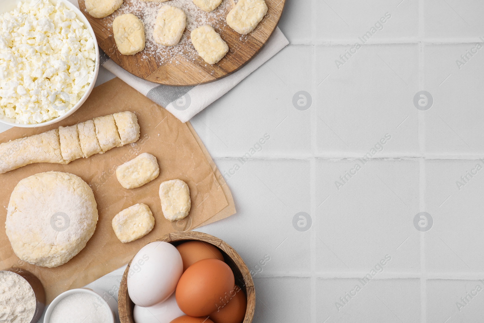 Photo of Making lazy dumplings. Raw dough and ingredients on white tiled table, flat lay. Space for text