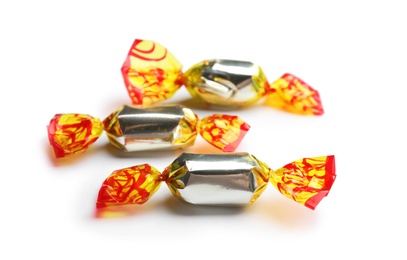 Delicious candies wrapped in foil on white background