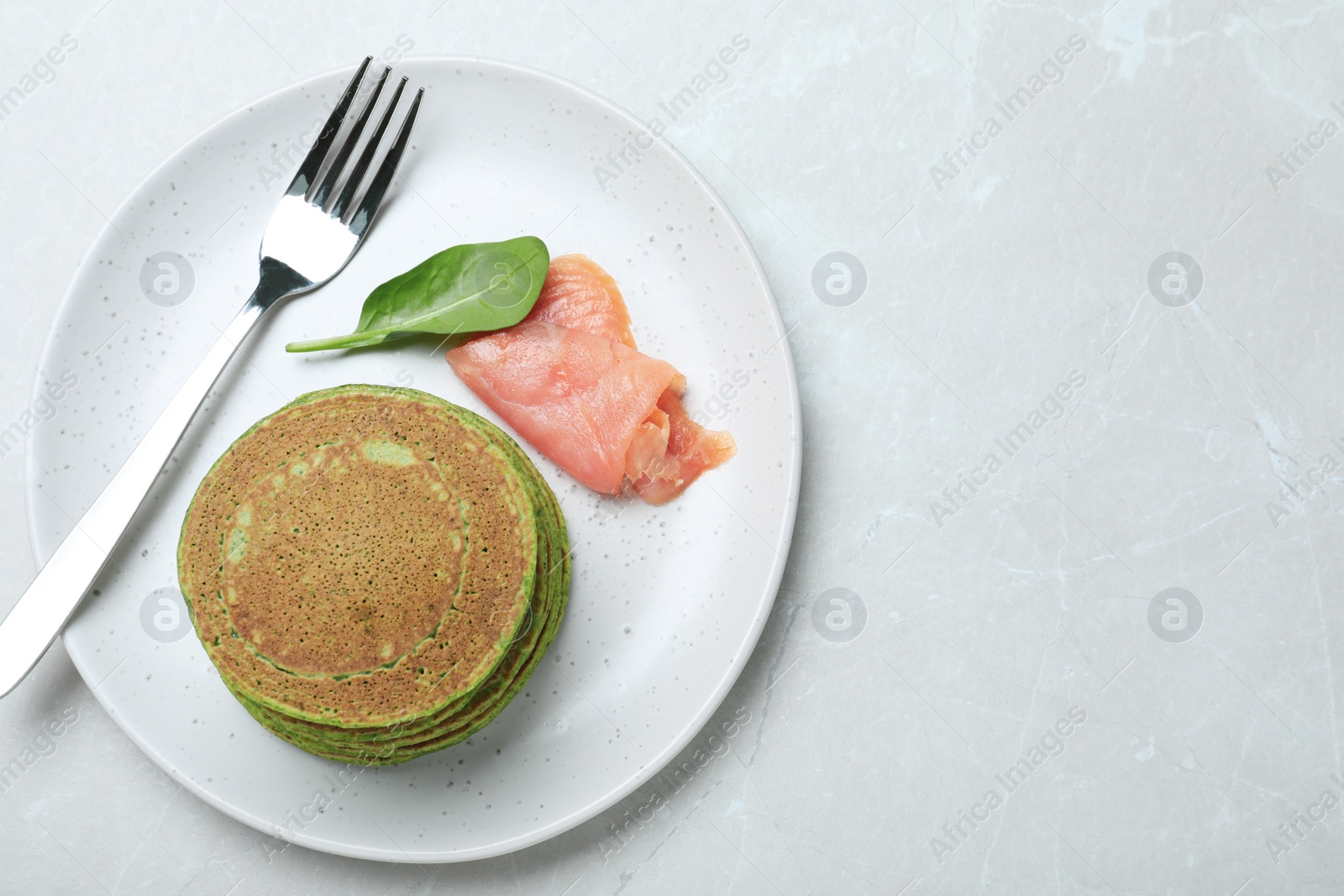 Photo of Tasty spinach pancakes served on light grey marble table, top view. Space for text