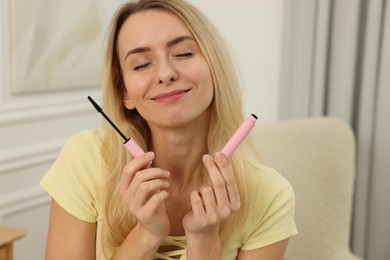 Photo of Beautiful smiling woman with mascara at home