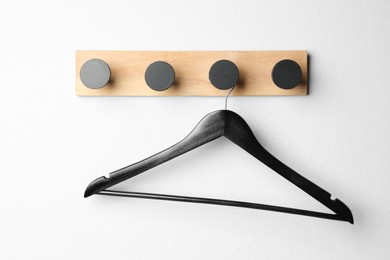 Photo of Rack with empty black clothes hanger on white wall