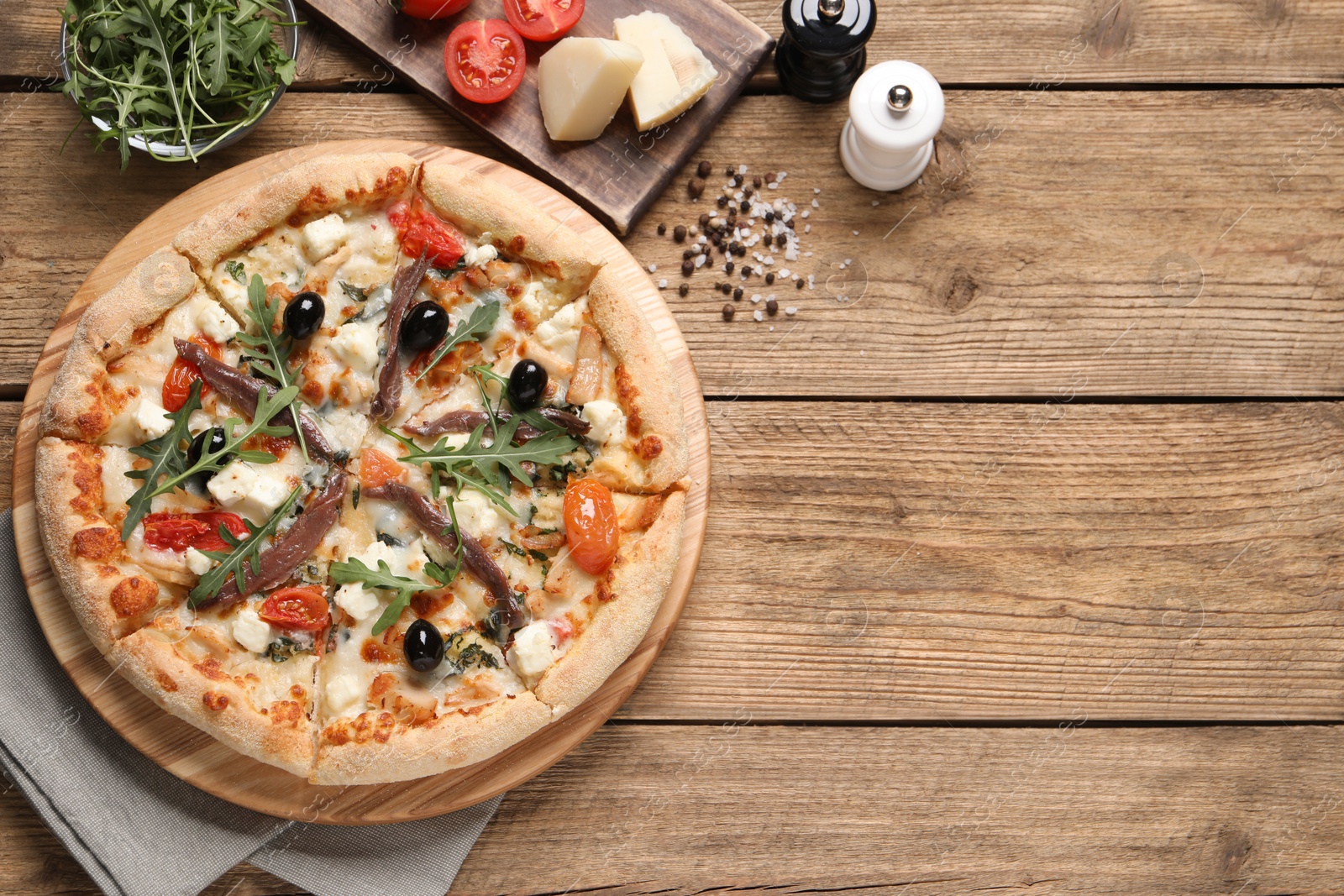 Photo of Tasty pizza with anchovies and ingredients on wooden table, flat lay. Space for text