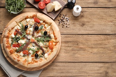 Tasty pizza with anchovies and ingredients on wooden table, flat lay. Space for text