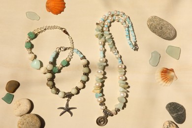 Photo of Flat lay composition with different beautiful bracelets and necklace with gemstones on beige background