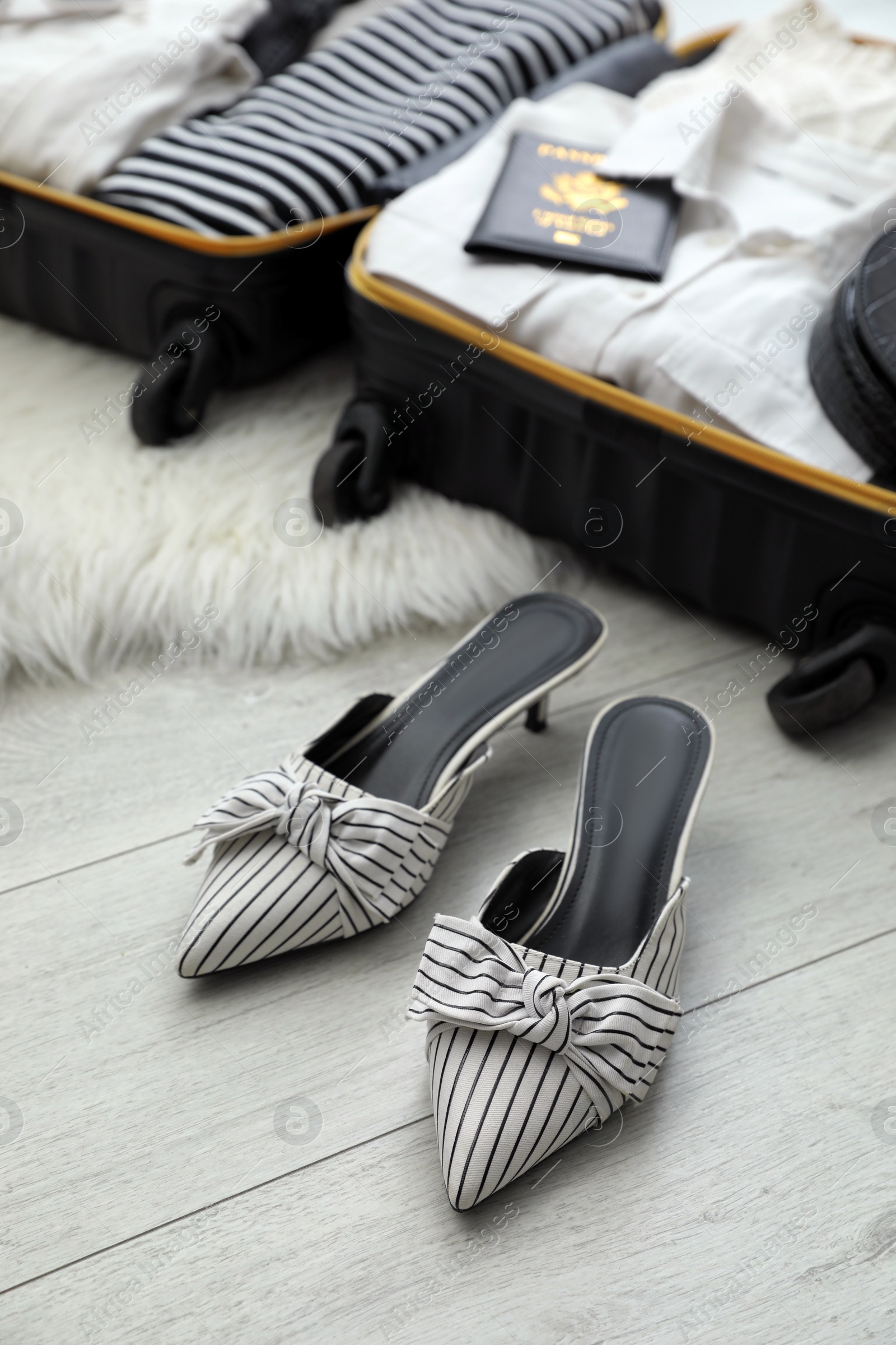 Photo of Stylish shoes near open suitcase packed for trip on floor