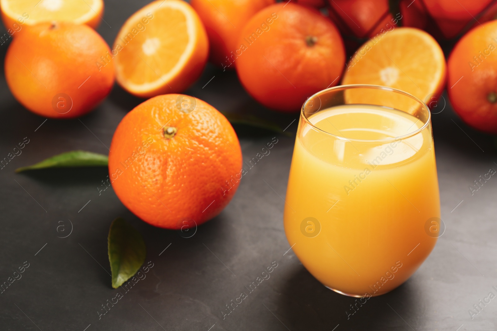 Photo of Delicious orange juice and fresh fruits on black table