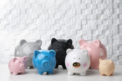 Photo of Different cute piggy banks on table against wall