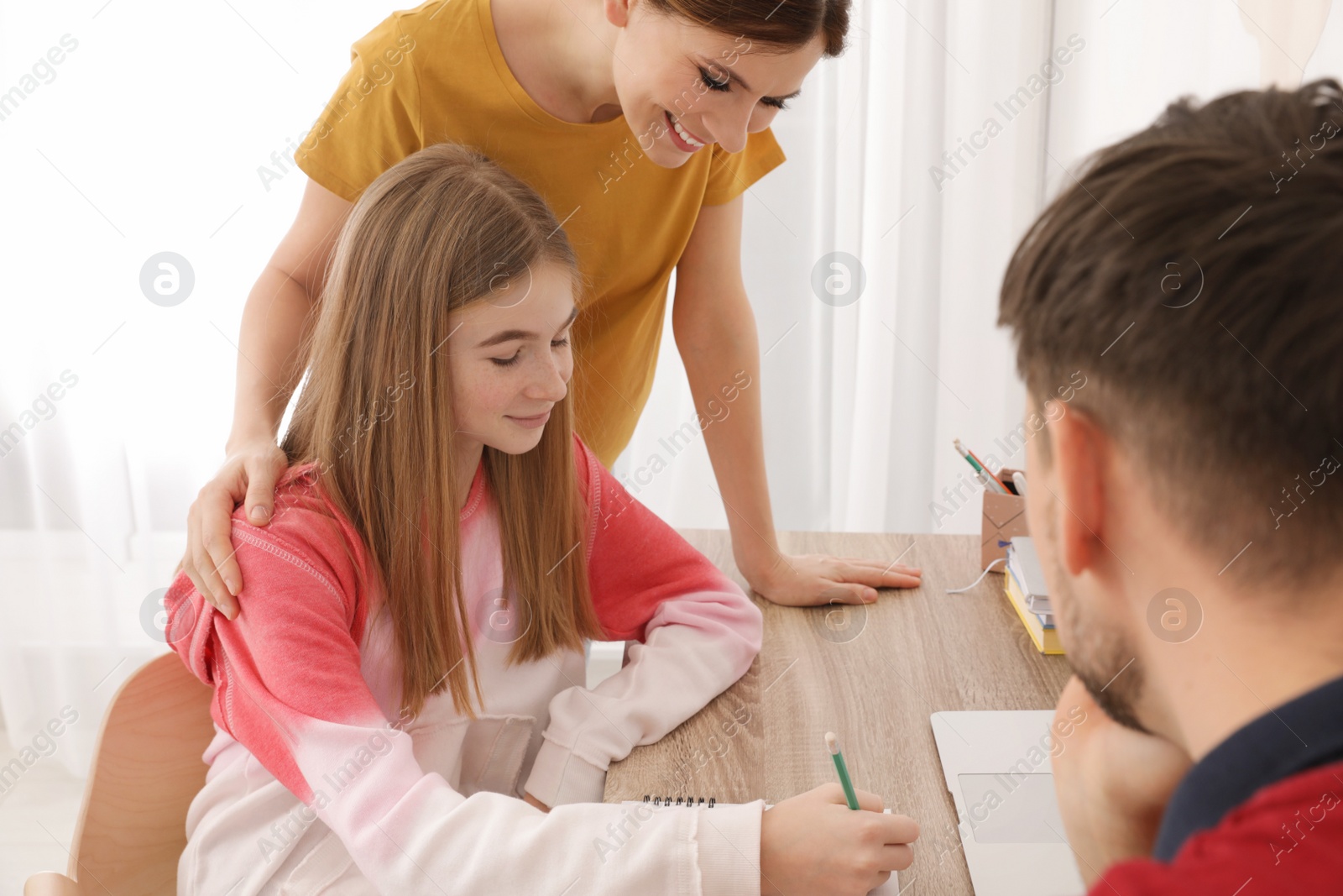Photo of Parents helping their teenager daughter with homework indoors