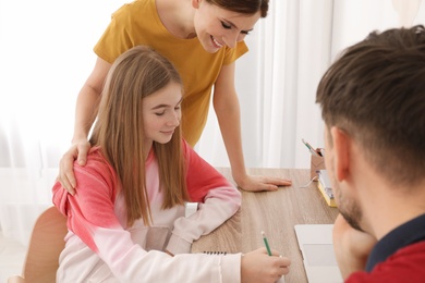 Parents helping their teenager daughter with homework indoors