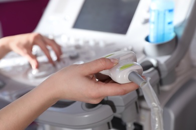 Photo of Sonographer holding ultrasound machine probe in clinic, closeup