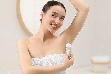 Photo of Beautiful young woman applying deodorant in bathroom