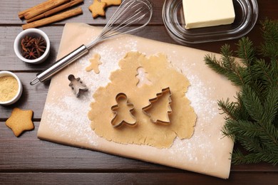 Photo of Making Christmas cookies. Flat lay composition with cutters and raw dough on wooden table