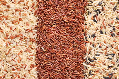 Mix of different brown rice as background, top view