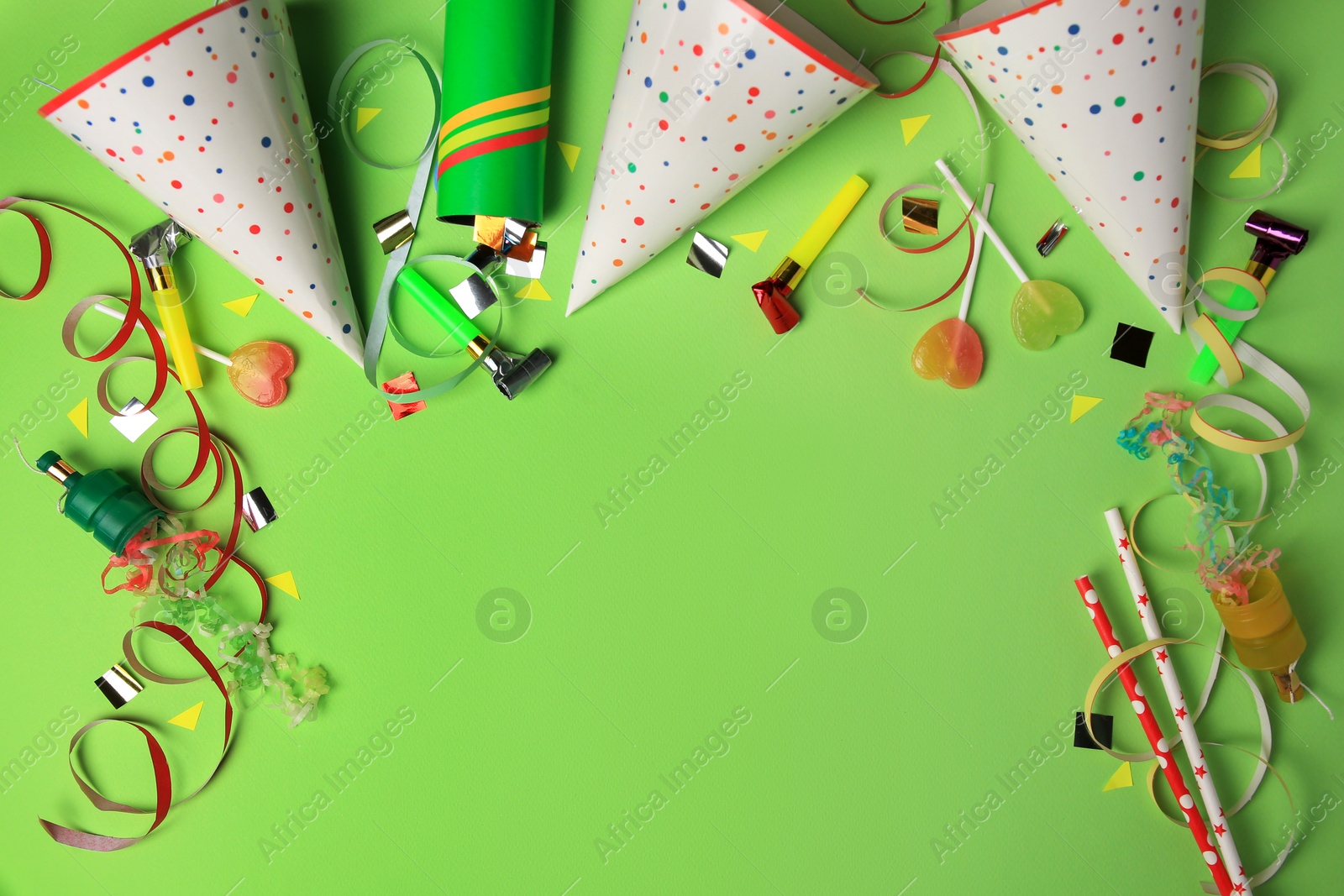 Photo of Party poppers with colorful streamers, blowers and festive decor on light green background, flat lay. Space for text