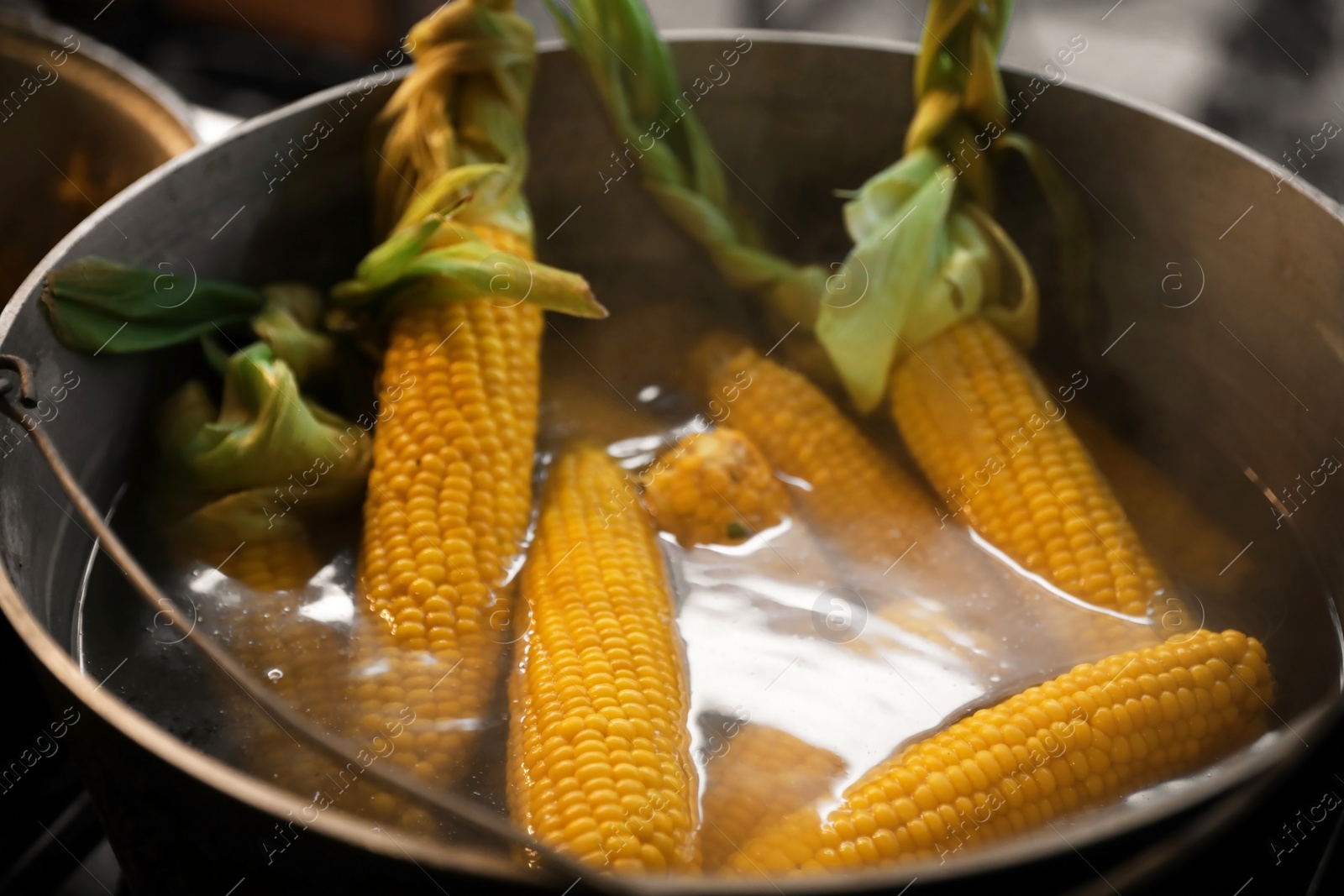 Photo of Delicious fresh corn cobs in pot with hot water, closeup