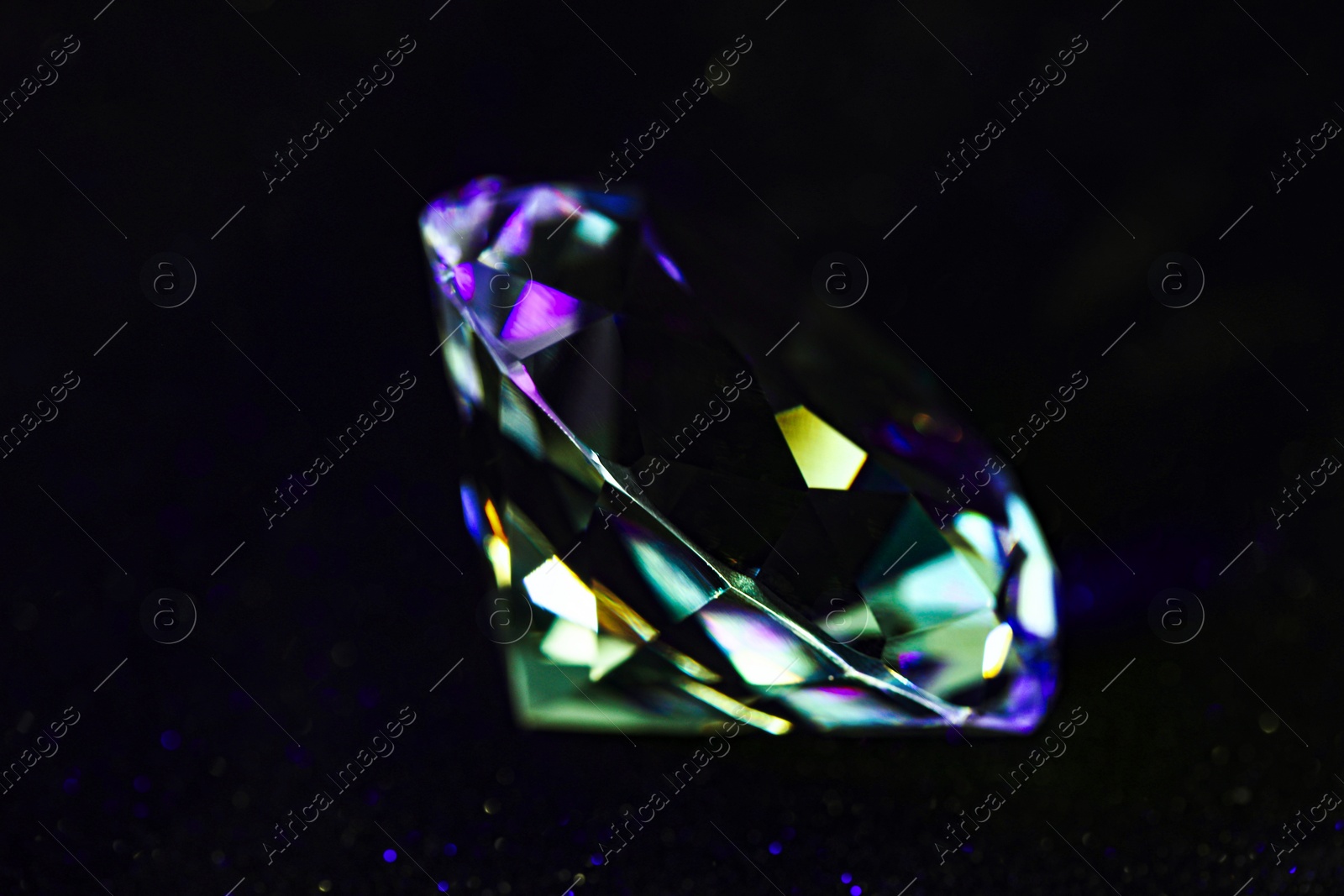 Photo of Beautiful dazzling diamond on black glitter surface, closeup