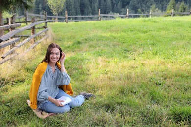 Photo of Beautiful young woman drawing with pencil in notepad on green grass