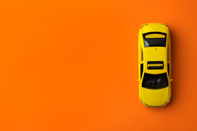 Yellow taxi car model on orange background, top view. Space for text