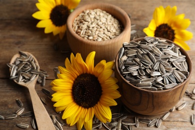 Photo of Organic sunflower seeds and flowers on wooden table