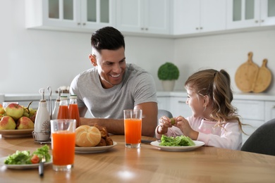 Father with daughter having breakfast together at table in modern kitchen