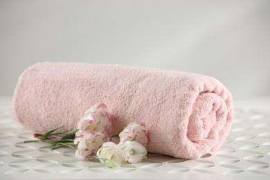 Photo of Rolled soft towel and eustoma flowers on white table