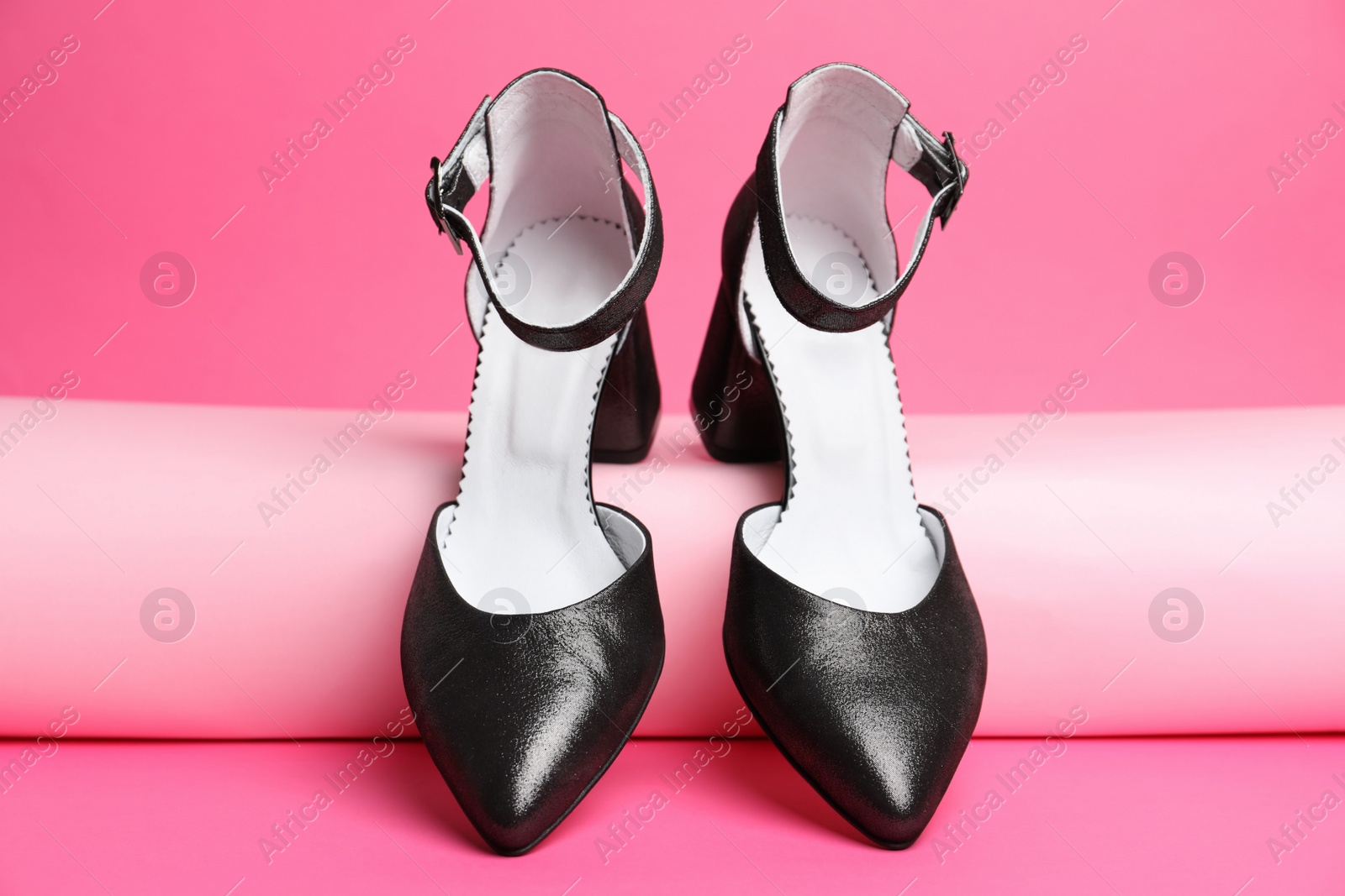 Photo of Stylish black female shoes on pink background