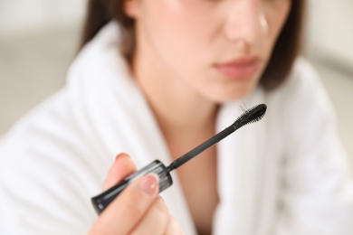 Photo of Young woman holding mascara brush with fallen eyelashes, closeup