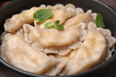 Photo of Bowl of delicious dumplings (varenyky) with cottage cheese and mint, closeup