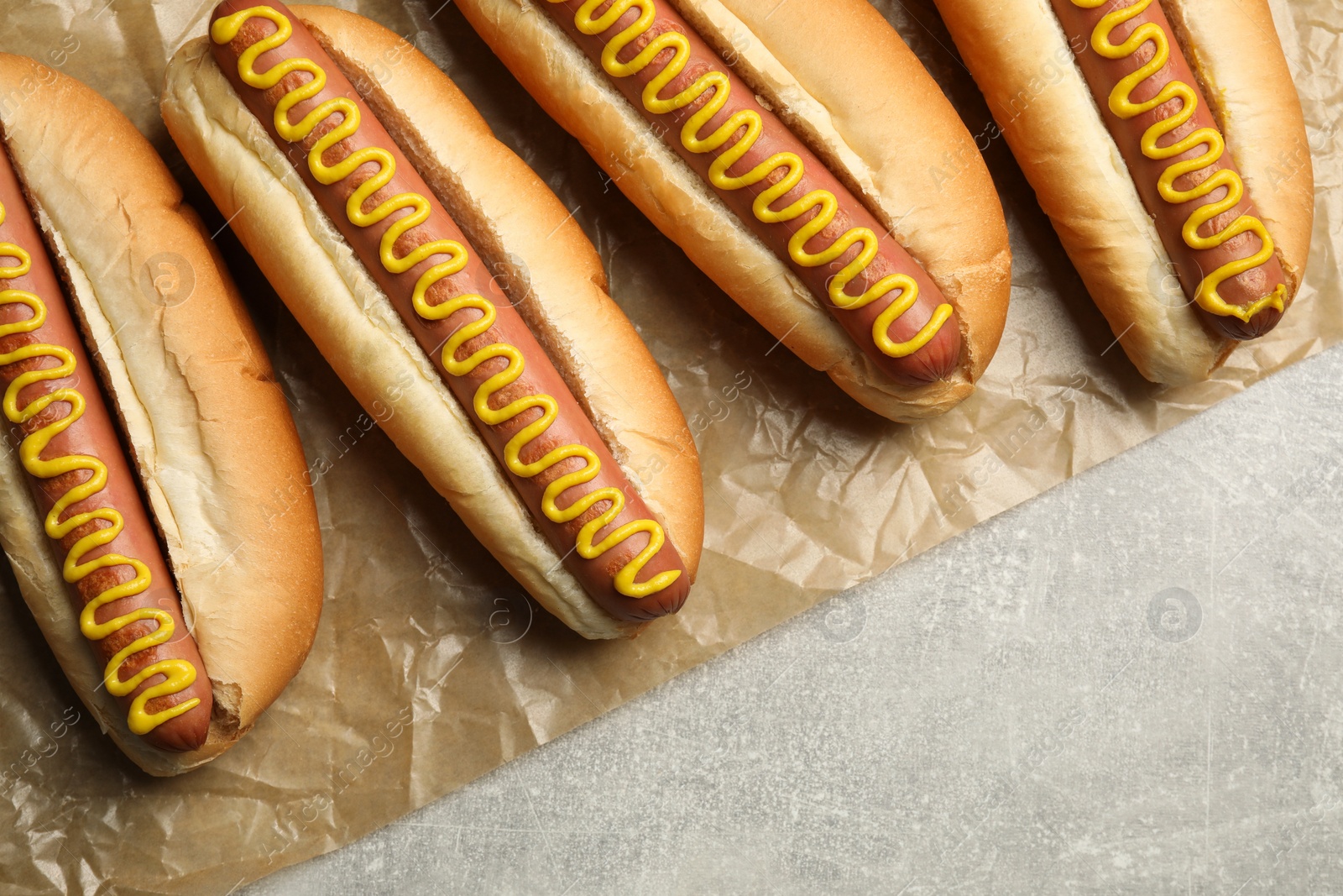 Photo of Fresh delicious hot dogs with mustard on light grey table, top view