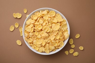 Photo of Breakfast cereal. Tasty corn flakes in bowl on brown table, top view