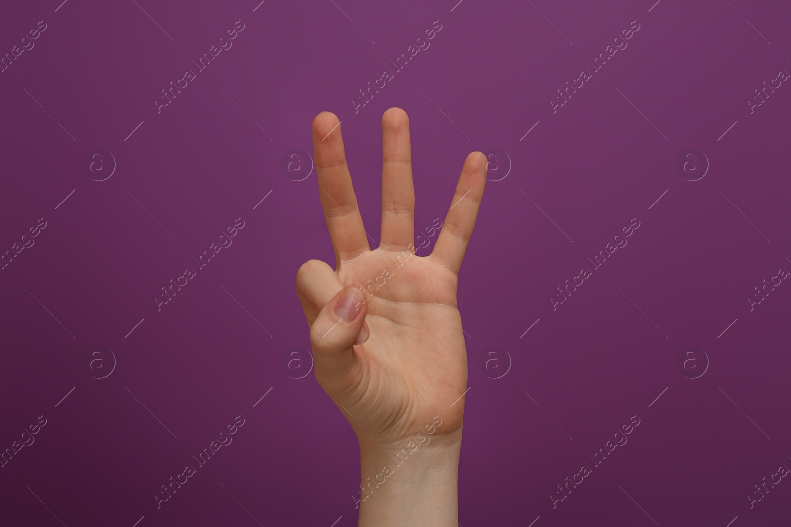 Photo of Woman showing three fingers on purple background, closeup