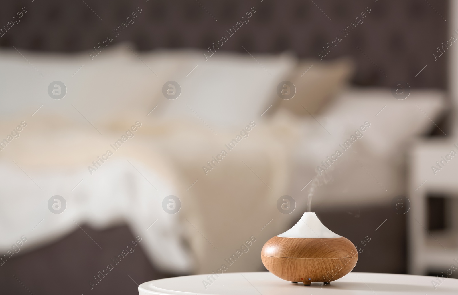 Photo of Aroma oil diffuser lamp on table against blurred background