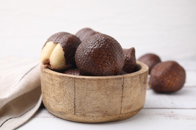 Fresh salak fruits in bowl on white wooden table, closeup