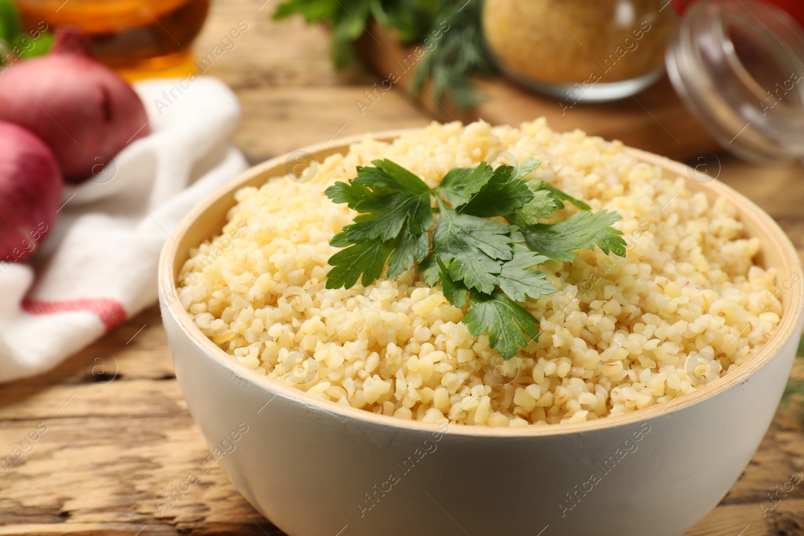 Photo of Delicious bulgur with parsley on wooden table, closeup